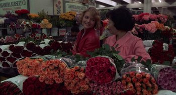 Movie still from “Into the Night” (1985), directed by John Landis – Two women are standing in front of a display of roses; Wide shot, Over the shoulder angle