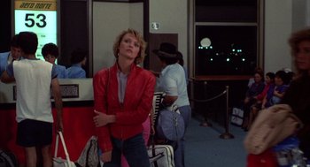 Movie still from “Into the Night” (1985), directed by John Landis – A woman in a red leather jacket standing next to two other women; Medium shot, Over the shoulder angle