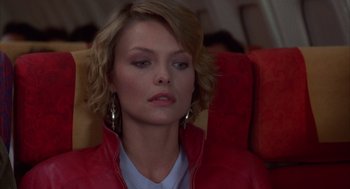 Movie still from “Into the Night” (1985), directed by John Landis – A woman sitting in a chair on a plane; Close Up shot, High angle