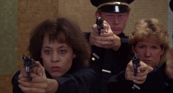 Movie still from “Into the Night” (1985), directed by John Landis – A group of people in uniform holding guns; Medium shot, Low angle