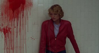 Movie still from “Into the Night” (1985), directed by John Landis – A woman in red jacket leaning against a wall; Medium shot, High angle