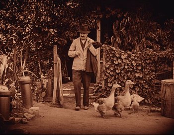 Movie still from “Intolerance” (1916), directed by D.W. Griffith – An old photo of a man and ducks in a yard; Wide shot, Low angle