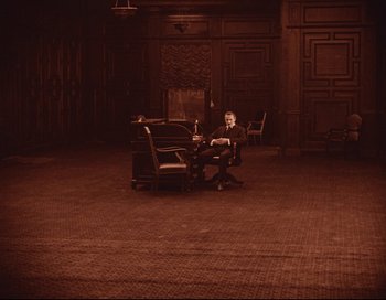 Movie still from “Intolerance” (1916), directed by D.W. Griffith – A man sitting in a chair in a room; Extreme Wide shot, High angle