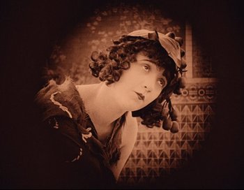 Movie still from “Intolerance” (1916), directed by D.W. Griffith – An old photograph of a woman with a hat on; Close Up shot, High angle