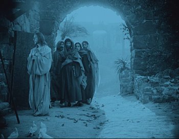 Movie still from “Intolerance” (1916), directed by D.W. Griffith – A group of people standing in the snow near an archway; Wide shot, Low angle