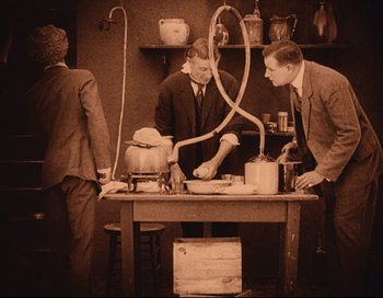 Movie still from “Intolerance” (1916), directed by D.W. Griffith – A group of men standing around a wooden table; Medium shot, Low angle