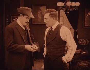Movie still from “Intolerance” (1916), directed by D.W. Griffith – Two men in suits and hats are talking to each other; Medium shot, High angle