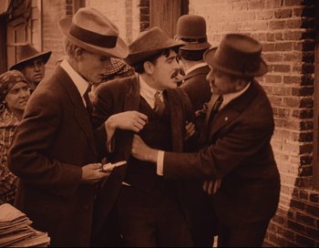 Movie still from “Intolerance” (1916), directed by D.W. Griffith – A group of men in suits and hats are fighting; Medium shot, Low angle