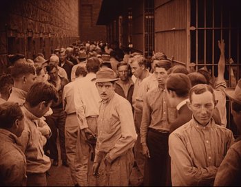 Movie still from “Intolerance” (1916), directed by D.W. Griffith – A group of men standing next to each other in a building; Wide shot, High angle