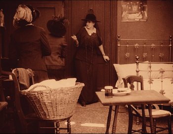 Movie still from “Intolerance” (1916), directed by D.W. Griffith – An old photo of a woman in a room; Wide shot, High angle