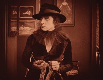 Movie still from “Intolerance” (1916), directed by D.W. Griffith – An old photo of a woman in a hat holding a scarf; Medium shot, Low angle
