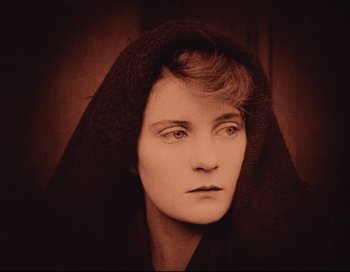 Movie still from “Intolerance” (1916), directed by D.W. Griffith – An old photo of a woman wearing a black robe; Close Up shot, High angle