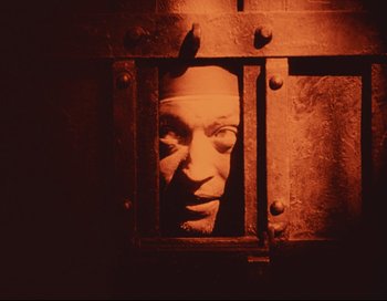 Movie still from “Intolerance” (1916), directed by D.W. Griffith – A man's face is seen through a metal door; Close Up shot, High angle