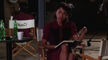Movie still from “Introducing Dorothy Dandridge” (1999), directed by Martha Coolidge – A woman sitting in a chair holding a book; Medium shot, Over the shoulder angle