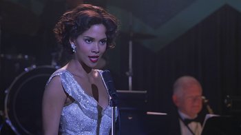 Movie still from “Introducing Dorothy Dandridge” (1999), directed by Martha Coolidge – A woman in a silver dress holding a microphone; Close Up shot, Over the shoulder angle