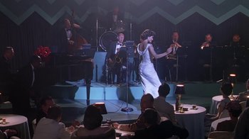 Movie still from “Introducing Dorothy Dandridge” (1999), directed by Martha Coolidge – A woman in a white dress singing in front of an audience; Wide shot, High angle
