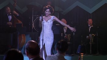 Movie still from “Introducing Dorothy Dandridge” (1999), directed by Martha Coolidge – A woman in a white dress singing into a microphone; Medium shot, Low angle