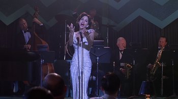 Movie still from “Introducing Dorothy Dandridge” (1999), directed by Martha Coolidge – A woman in a white dress singing into a microphone; Medium shot, Low angle