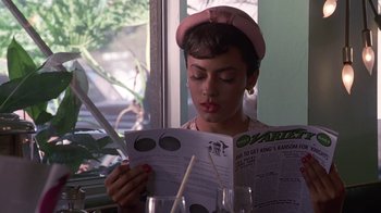 Movie still from “Introducing Dorothy Dandridge” (1999), directed by Martha Coolidge – A woman reading a newspaper at a table; Close Up shot, Over the shoulder angle