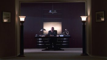 Movie still from “Introducing Dorothy Dandridge” (1999), directed by Martha Coolidge – A man sitting at a desk in front of a lamp; Wide shot, Low angle