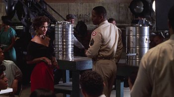 Movie still from “Introducing Dorothy Dandridge” (1999), directed by Martha Coolidge – A man and a woman standing next to each other in front of metal barrels; Medium shot, Over the shoulder angle