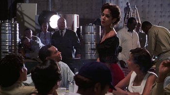Movie still from “Introducing Dorothy Dandridge” (1999), directed by Martha Coolidge – A woman standing in front of a group of people; Medium shot, Over the shoulder angle