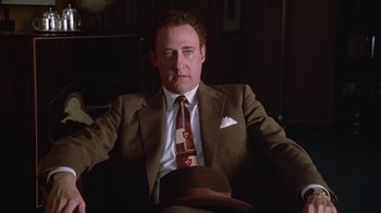 Movie still from “Introducing Dorothy Dandridge” (1999), directed by Martha Coolidge – A man in a suit and tie sitting in a chair; Medium shot, Low angle