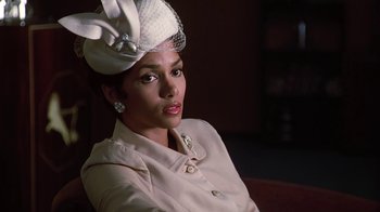 Movie still from “Introducing Dorothy Dandridge” (1999), directed by Martha Coolidge – A woman wearing a white hat sitting on a couch; Close Up shot, Low angle