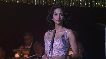 A woman standing in front of a microphone in front of a group of people