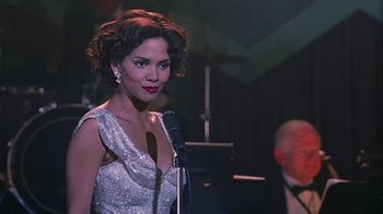 Movie still from “Introducing Dorothy Dandridge” (1999), directed by Martha Coolidge – A woman in a silver dress holding a microphone; Close Up shot, Over the shoulder angle