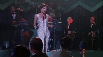 Movie still from “Introducing Dorothy Dandridge” (1999), directed by Martha Coolidge – A woman in a white dress singing into a microphone in front of an orchestra; Medium shot, Low angle