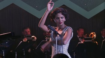 Movie still from “Introducing Dorothy Dandridge” (1999), directed by Martha Coolidge – A woman in a white dress holding a microphone up in the air; Medium shot, Low angle