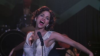 Movie still from “Introducing Dorothy Dandridge” (1999), directed by Martha Coolidge – A woman in a silver dress singing into a microphone; Medium shot, Low angle
