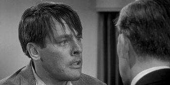 Movie still from “Invasion of the Body Snatchers” (1956), directed by Don Siegel – A black - and - white photo of a man in a suit and tie; Close Up shot, Over the shoulder angle
