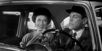 Movie still from “Invasion of the Body Snatchers” (1956), directed by Don Siegel – A man and a woman sitting in the drivers seat of a car; Medium shot, Low angle