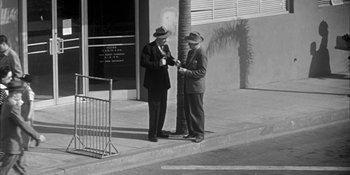 Movie still from “Invasion of the Body Snatchers” (1956), directed by Don Siegel – A couple of men standing next to each other on a sidewalk; Wide shot, High angle