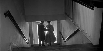 Movie still from “Invasion of the Body Snatchers” (1956), directed by Don Siegel – A man and a woman standing on the stairs; Wide shot, Low angle