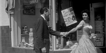 Movie still from “Invasion of the Body Snatchers” (1956), directed by Don Siegel – A man and woman shaking hands in front of a store window; Medium shot, Over the shoulder angle