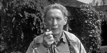 Movie still from “Invasion of the Body Snatchers” (1956), directed by Don Siegel – An older man smoking a cigarette in front of a building; Close Up shot, Low angle