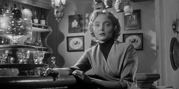 Movie still from “Invasion of the Body Snatchers” (1956), directed by Don Siegel – A black and white photo of a woman sitting at a table; Close Up shot, Low angle