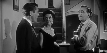 Movie still from “Invasion of the Body Snatchers” (1956), directed by Don Siegel – A man and a woman standing next to each other in front of a staircase; Medium shot, Over the shoulder angle