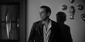 Movie still from “Invasion of the Body Snatchers” (1956), directed by Don Siegel – Black and white photograph of a man wearing a leather jacket; Medium shot, Low angle