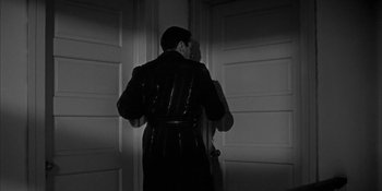Movie still from “Invasion of the Body Snatchers” (1956), directed by Don Siegel – A man standing in front of two doors; Medium shot, Low angle