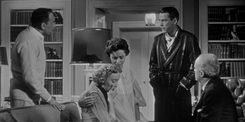 Movie still from “Invasion of the Body Snatchers” (1956), directed by Don Siegel – A group of people standing around a living room together; Medium shot, Low angle