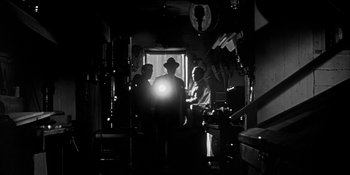 Movie still from “Invasion of the Body Snatchers” (1956), directed by Don Siegel – A group of men standing in a dimly - lit room; Wide shot, Low angle