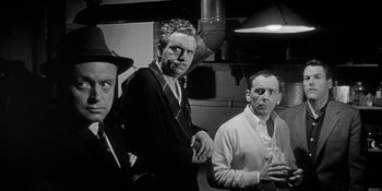 Movie still from “Invasion of the Body Snatchers” (1956), directed by Don Siegel – A black and white photo of a group of men standing next to each other; Medium shot, Low angle