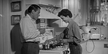 Movie still from “Invasion of the Body Snatchers” (1956), directed by Don Siegel – A man and a woman in the kitchen preparing a meal; Medium shot, Low angle