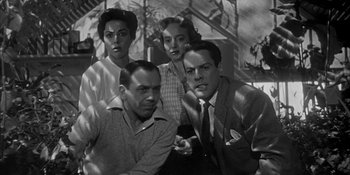 Movie still from “Invasion of the Body Snatchers” (1956), directed by Don Siegel – A black and white photo of a group of men and a woman; Medium shot, Low angle