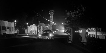 Movie still from “Invasion of the Body Snatchers” (1956), directed by Don Siegel – An old car driving down a street at night; Extreme Wide shot, Low angle