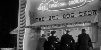 Movie still from “Invasion of the Body Snatchers” (1956), directed by Don Siegel – Three people standing in front of a hot dog stand; Wide shot, High angle